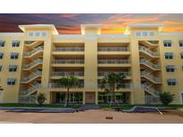 Beautiful yellow condo building featuring open-air hallways and staircases, as well as manicured landscaping at 280 Hidden Bay Dr # 203, Osprey, FL 34229