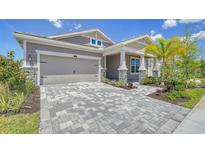 Two-story home with gray siding, stone accents, and a paved driveway at 5770 Long Shore Loop, Sarasota, FL 34238