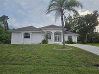 Charming single-story home with a well-maintained lawn and a beautiful palm tree in the front yard at 15 Tee View Pl, Rotonda West, FL 33947