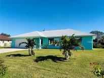 Charming light blue house with a white roof, landscaping, and a two-car garage at 1415 Piedmont Rd, Venice, FL 34293