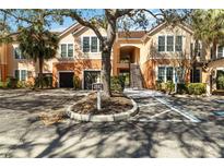 Two-story condo with garages and a covered entrance, framed by mature trees and landscaping at 4102 Central Sarasota Pkwy # 926, Sarasota, FL 34238