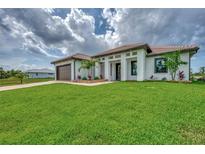 Single-story home with attached garage, lush lawn, and attractive landscaping at 15504 Hennipen Cir, Port Charlotte, FL 33981