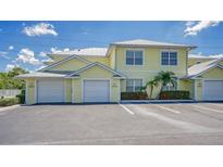 Front view of a yellow two-story building with two garages at 16450 Gloria Ln # 105, Nokomis, FL 34275