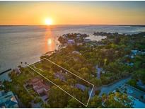 Stunning aerial view of a luxury waterfront estate at sunset, surrounded by lush greenery and offering serene coastal living at 4521 Bay Shore Rd, Sarasota, FL 34234