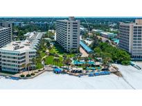 Aerial view of beachfront condo building with pool and tennis courts at 5920 Midnight Pass Rd # 104, Sarasota, FL 34242