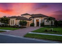 Stunning two-story house with a brick driveway, under a beautiful sunset at 5309 Greenbrook Dr, Sarasota, FL 34238