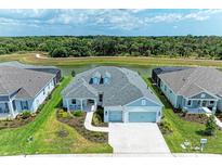 Aerial view of a light blue house with a three-car garage, situated on a pond at 14359 Skipping Stone Loop, Parrish, FL 34219