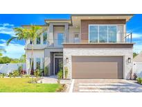 Modern two-story home with a light stone facade, wood accents, balcony, and well-manicured landscaping at 1805 Goldenrod St, Sarasota, FL 34239
