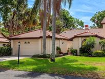 Well-maintained house with a tiled roof, lush landscaping, and a two-car garage at 7360 Oak Moss Dr # 4, Sarasota, FL 34241