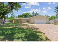 Charming single-story home featuring a brick driveway, attached two-car garage, and well-maintained landscaping at 808 Ponderosa Pine Ln, Sarasota, FL 34243