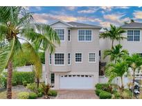 Tan three-story house with white garage door and palm trees at 219 81St St, Holmes Beach, FL 34217