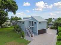 Beautiful two-story coastal home with a light blue exterior, metal roof, and a paver driveway at 4343 Pompano Ln, Palmetto, FL 34221