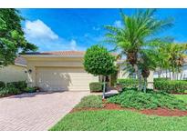 Tan house with lush landscaping and a brick paved driveway at 350 River Enclave Ct, Bradenton, FL 34212