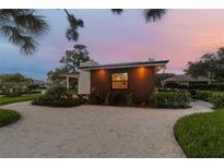 Modern cottage at dusk with lighted window and gravel driveway at 301 Aurora E St, Venice, FL 34285