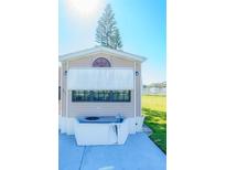 Exterior view of a tan mobile home with a grassy yard and AC unit at 207 Crown Point Dr, Nokomis, FL 34275