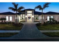 Luxury home with modern design, a paved driveway, and lush landscaping at 1158 Blue Shell Loop, Sarasota, FL 34240