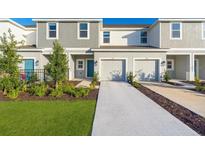 Two-story townhome with gray siding, two-car garage, and landscaped lawn at 3145 Novara Ln, Lakewood Ranch, FL 34211