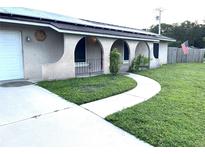 House exterior with a white garage door, arched entryway and green lawn at 5029 Webber St, Sarasota, FL 34232