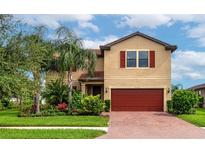 Two-story house with red garage door and landscaping at 2352 Marton Oak Blvd, North Port, FL 34289
