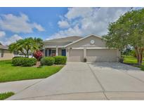Charming single-story home featuring a manicured lawn, mature trees, and a spacious three-car garage at 11622 Summit Rock Ct, Parrish, FL 34219