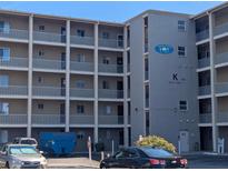 A condominium building with a parking lot showing balconies and a sign, 