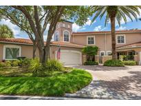 Tan three-story townhome with a white garage door and landscaped front yard at 1711 Starling Dr # 1711, Sarasota, FL 34231