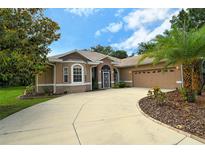 House exterior featuring a light brown facade, three-car garage, and mature landscaping at 815 128Th Ne St, Bradenton, FL 34212