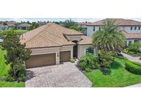 Charming home featuring a tile roof, brick driveway, two-car garage and well-manicured landscaping at 13215 Ramblewood Trl, Bradenton, FL 34211