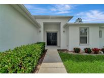 Home's front entrance with walkway and lush landscaping at 1174 S Mcduff St, North Port, FL 34288