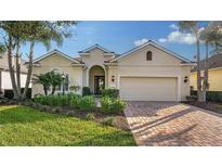 Tan single-story home with brick driveway and landscaping at 7275 Lismore Ct, Lakewood Ranch, FL 34202