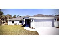 Beautiful one-story home showcasing a well-manicured lawn, a two-car garage, and a welcoming walkway to the front door at 3884 S Haberland Blvd, North Port, FL 34288