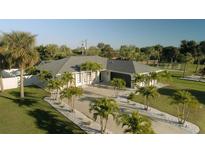 Aerial view of a single-story home with a large driveway and lush landscaping at 18770 Mcgrath Cir, Port Charlotte, FL 33948