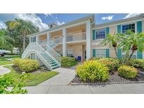 Two story condo building with teal accents, lush landscaping, and walkway at 4211 Caddie E Dr # 202, Bradenton, FL 34203