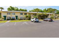 Exterior view of a light yellow condominium building with parking at 4805 Rilma Ave # 104, Sarasota, FL 34234