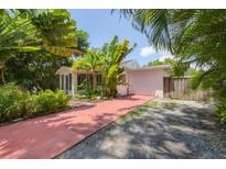 Home exterior with pink garage and red brick driveway, surrounded by tropical landscaping at 839 40Th St, Sarasota, FL 34234