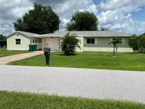 Ranch-style home with a green exterior, mature landscaping, and a two-car garage at 2350 Talbrook Ter, Punta Gorda, FL 33983