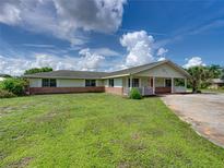 Brick ranch house with a green exterior, red door and carport at 1499 17Th W St, Palmetto, FL 34221