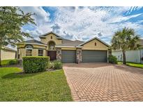 Two-story house with three car garage, brick driveway and landscaped lawn at 5514 69Th E Pl, Ellenton, FL 34222