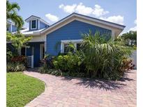 Charming blue house with brick paver driveway and lush landscaping at 213 75Th St, Holmes Beach, FL 34217