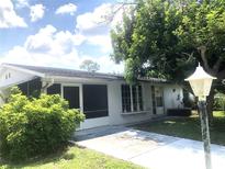 Ranch-style home with a screened porch and mature landscaping at 2434 Fourwind St, Port Charlotte, FL 33948