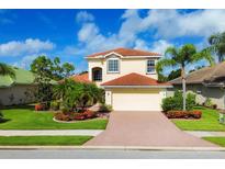 Charming two-story home with lush landscaping, terracotta roof, and a brick paver driveway at 11492 Dancing River Dr, Venice, FL 34292
