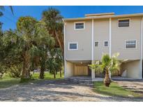 Tan three-story building with parking and tropical landscaping at 4001 Gulf Dr # 111, Holmes Beach, FL 34217