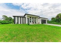 Modern house with a gray garage door and green lawn at 13457 Drysdale Ave, Port Charlotte, FL 33981