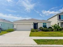 Charming one-story home with well-manicured lawn and two car garage and a blue sky above at 10827 Charlotte Dr, Parrish, FL 34219