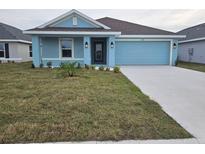Charming single-story home showcases a blue exterior, manicured lawn, and a two-car garage at 2616 Averland Loop, North Port, FL 34287