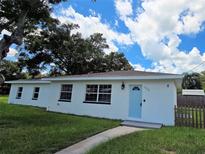 Newly renovated home with light blue door and landscaped yard at 100 N Duncan Ave, Clearwater, FL 33755