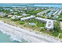 Aerial view of beachfront condo community with pool and lush landscaping at 5757 Gulf Of Mexico Dr # 109, Longboat Key, FL 34228