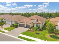 Beautiful single-Gathering home featuring a red tile roof, paver driveway, lush landscaping, and a two-car garage at 13212 Deep Blue Pl, Lakewood Ranch, FL 34211