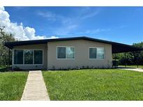 Tan house with black roof, landscaping, and walkway at 2708 Starlite Ln, Port Charlotte, FL 33952