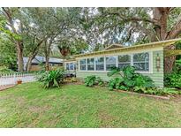 Charming bungalow featuring a large, tree-filled front yard and a bright, sunroom-style exterior at 1533 1St Ave W Dr, Bradenton, FL 34205